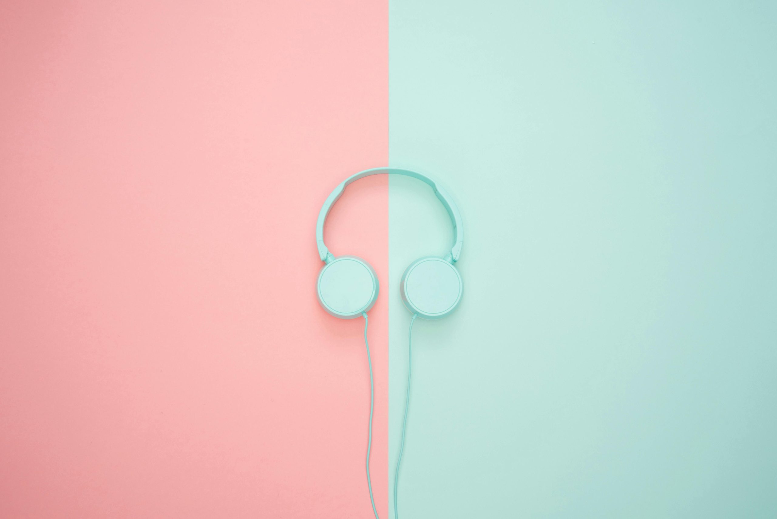 Minimalist headphones on a pink and mint background, artistic and modern.
